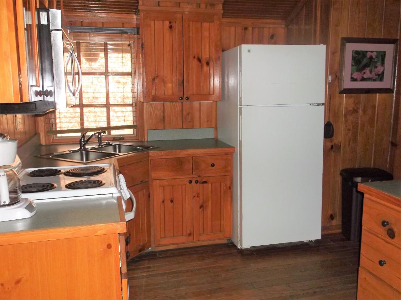A view of the kitchen in cabin 14 including a fridge, oven, microwave, and double sink